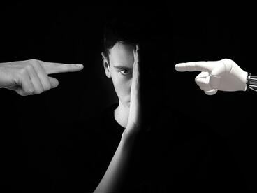 Ein Portrait wird durch eine Hand geteilt und eine menschlicher Finger zeigt von links und ein Roboterfinger von rechts auf das Gesicht.